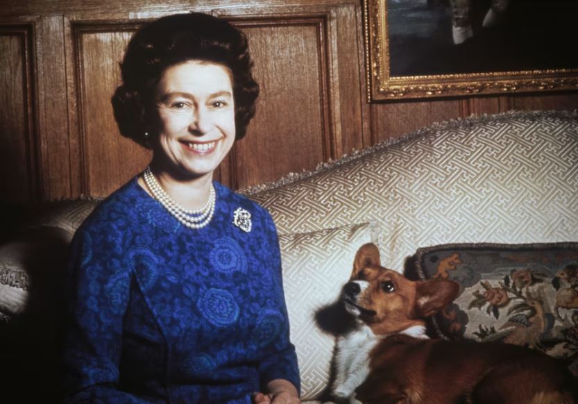 La reina Isabel II sentada junto a uno de sus corgis