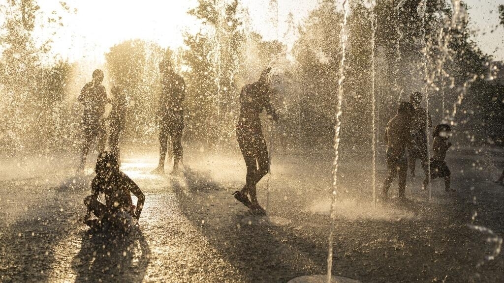 Los niños juegan con agua en una fuente durante una ola de calor en el centro de Atenas. Julio 21 de 2023.