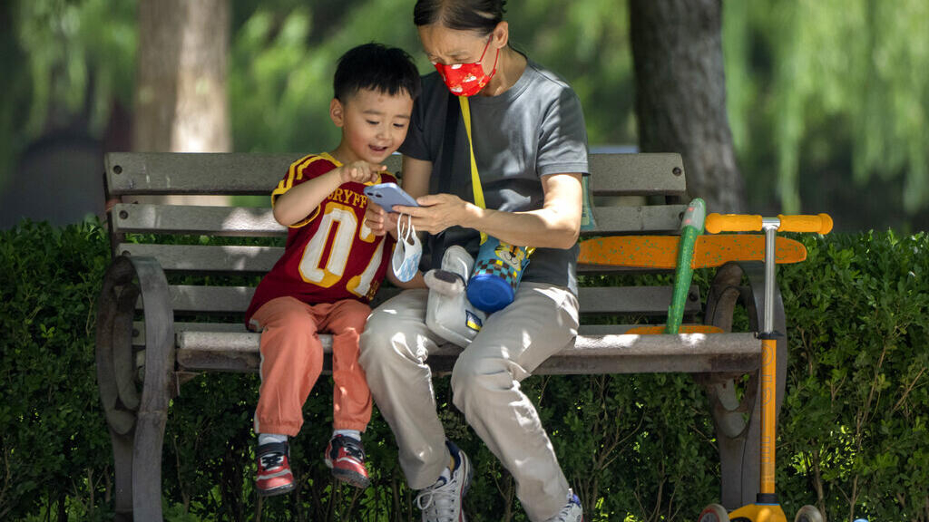 Une mujer y un niño atentos a la pantalla de un celular en un parque de Pekín, en junio de 2022. Foto de ilustración.