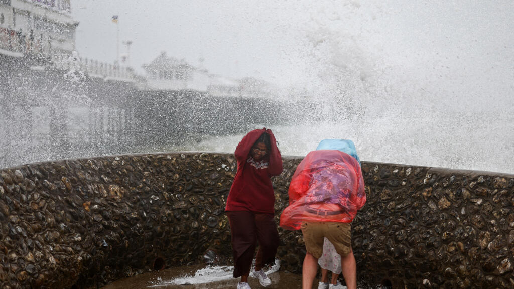 La gente reacciona mientras una ola golpea un malecón junto al Palace Pier en Brighton, al sur de Inglaterra, el 5 de agosto de 2023, mientras la tormenta Antoni trae lluvia y fuertes vientos al Reino Unido.