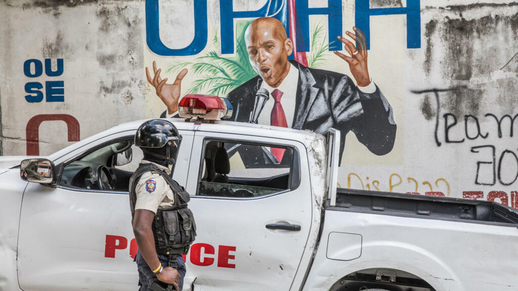 Un policía haitiano observa la imagen del asesinado presidente Jovenel Moise en un muro de Puerto Príncipe, el 15 de julio de 2021
